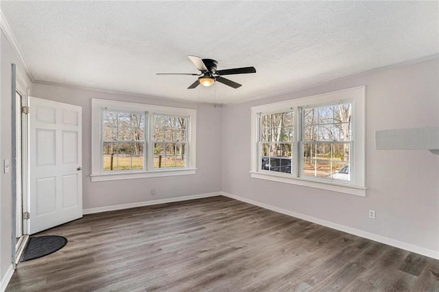 empty room featuring crown molding, ceiling fan, a textured ceiling, wood finished floors, and baseboards