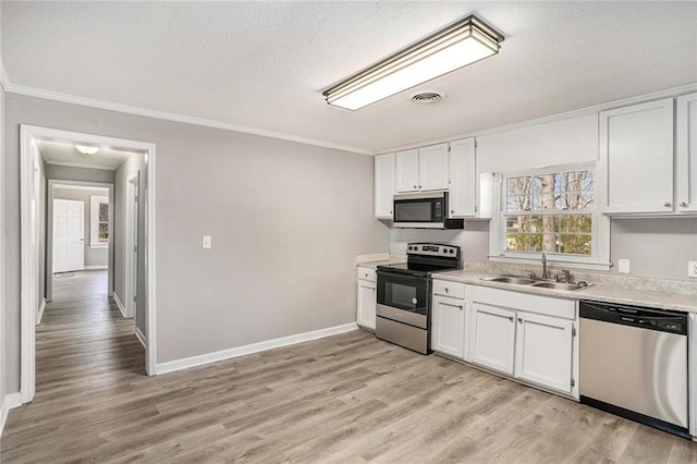 kitchen with a sink, white cabinetry, light countertops, appliances with stainless steel finishes, and light wood-type flooring