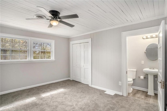 carpeted bedroom featuring a closet, ornamental molding, a sink, wooden ceiling, and baseboards