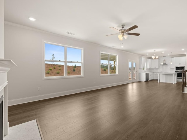 unfurnished living room featuring a fireplace with flush hearth, ornamental molding, dark wood-type flooring, and ceiling fan with notable chandelier