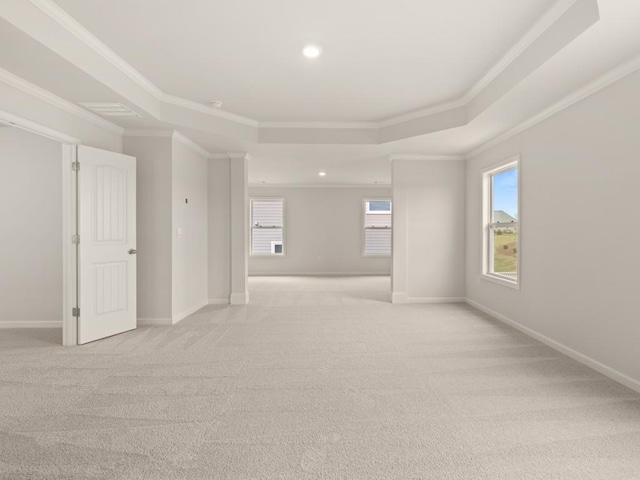 spare room with ornamental molding, a tray ceiling, baseboards, and light carpet