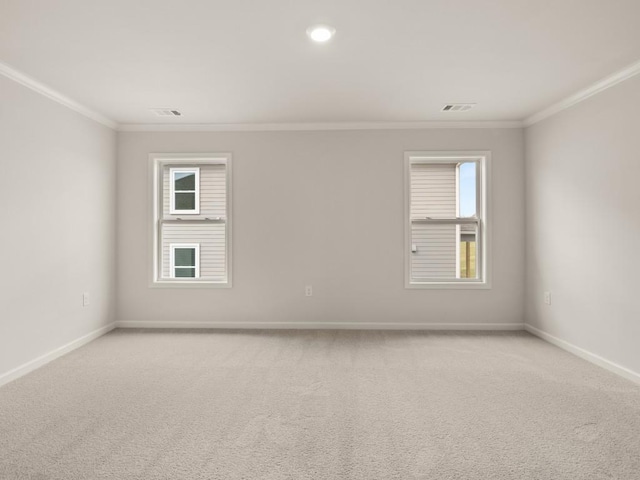spare room featuring ornamental molding, baseboards, light colored carpet, and visible vents