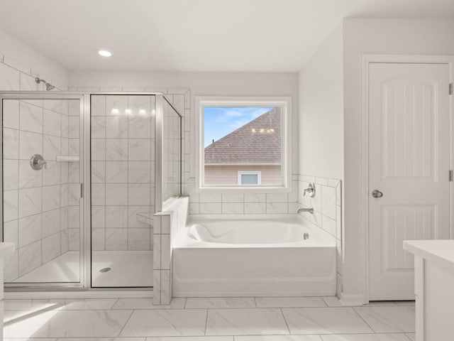 bathroom featuring marble finish floor, a shower stall, and a garden tub