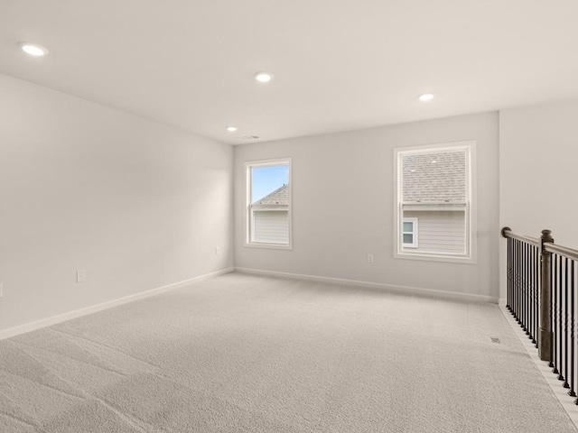 spare room with baseboards, recessed lighting, and light carpet