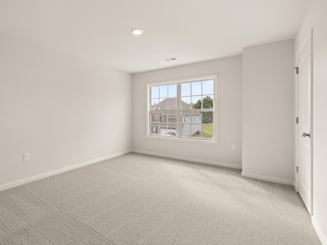 spare room with light carpet, baseboards, and visible vents