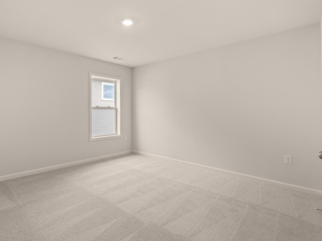 empty room featuring light colored carpet, visible vents, and baseboards