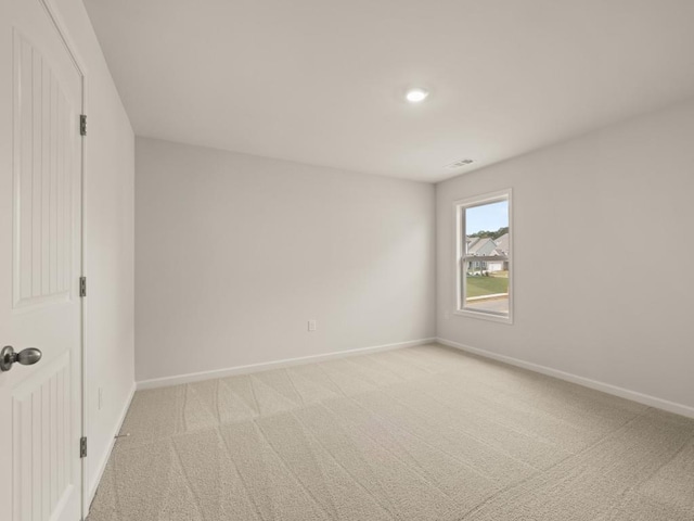 unfurnished room with baseboards, visible vents, and light colored carpet