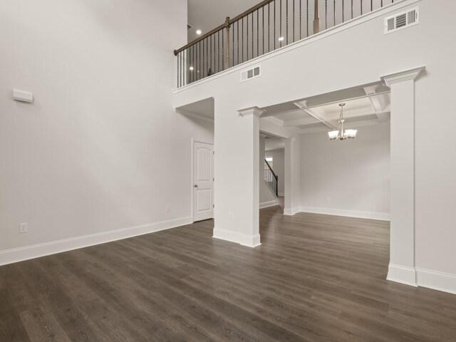 unfurnished living room featuring dark wood finished floors, baseboards, visible vents, and a notable chandelier