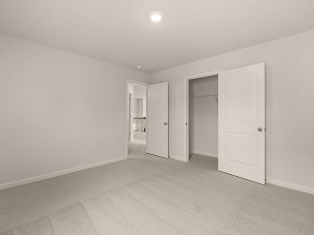 unfurnished bedroom featuring a closet, light carpet, and baseboards
