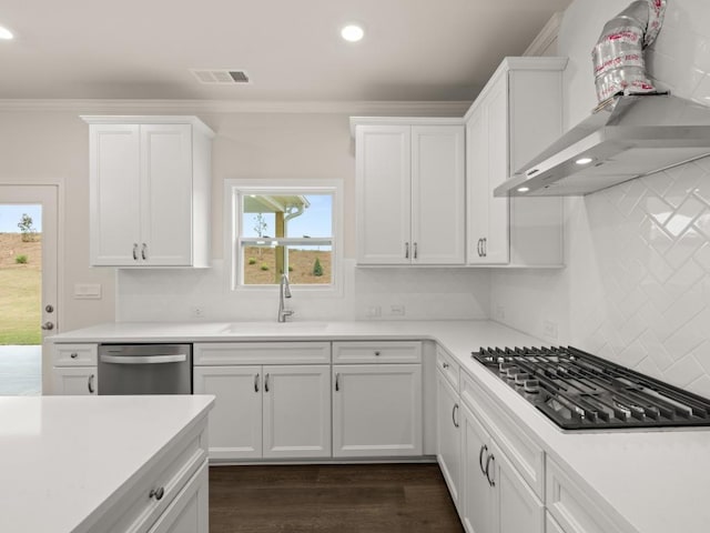kitchen with a sink, wall chimney exhaust hood, stainless steel appliances, visible vents, and ornamental molding