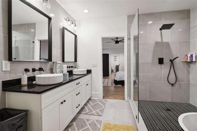 bathroom with tile patterned flooring, a tile shower, vanity, and ceiling fan