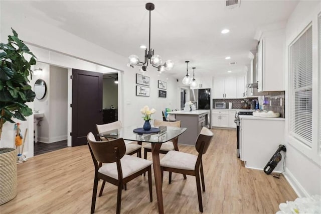 dining space featuring light hardwood / wood-style floors and a chandelier