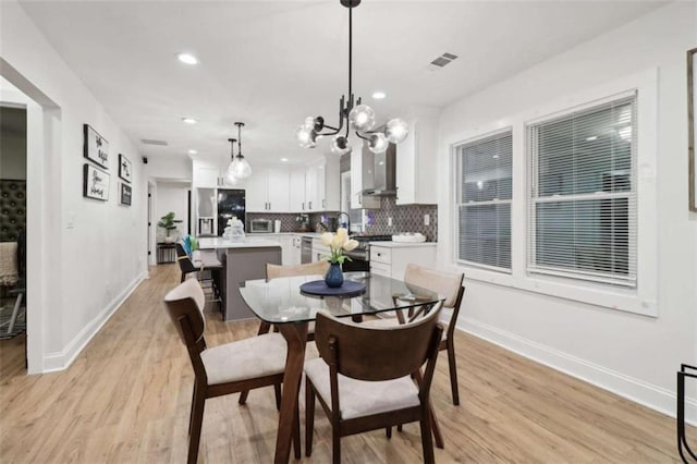 dining space with sink, a chandelier, and light wood-type flooring