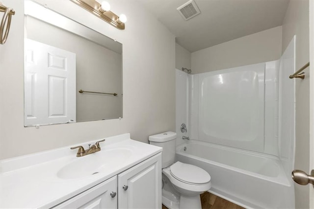 bathroom featuring visible vents, toilet, washtub / shower combination, vanity, and wood finished floors