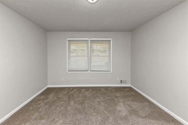 unfurnished room with a textured ceiling, dark colored carpet, visible vents, and baseboards