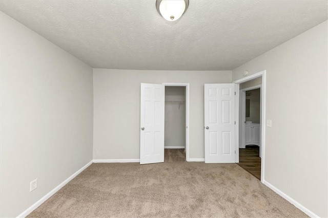 unfurnished bedroom with a textured ceiling, a closet, carpet flooring, and baseboards