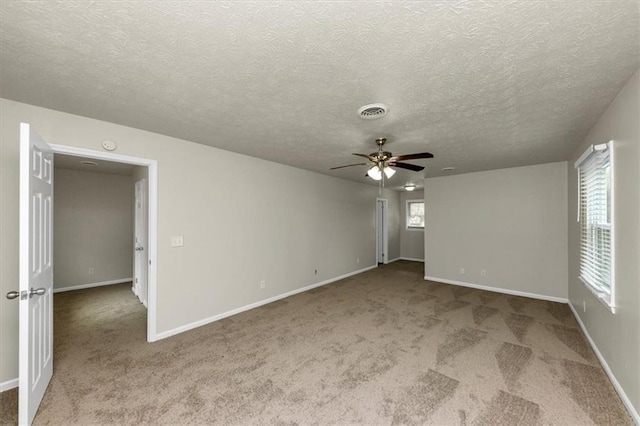 empty room with a ceiling fan, carpet flooring, visible vents, and baseboards