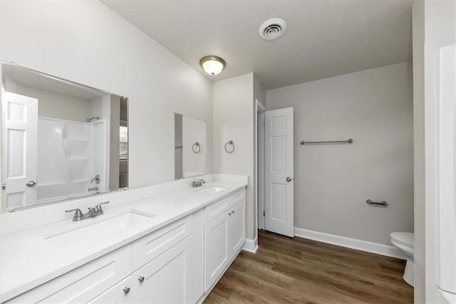 full bath with visible vents, toilet, wood finished floors, walk in shower, and a sink