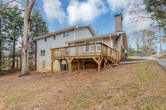 back of property with brick siding, a chimney, a wooden deck, and stairway