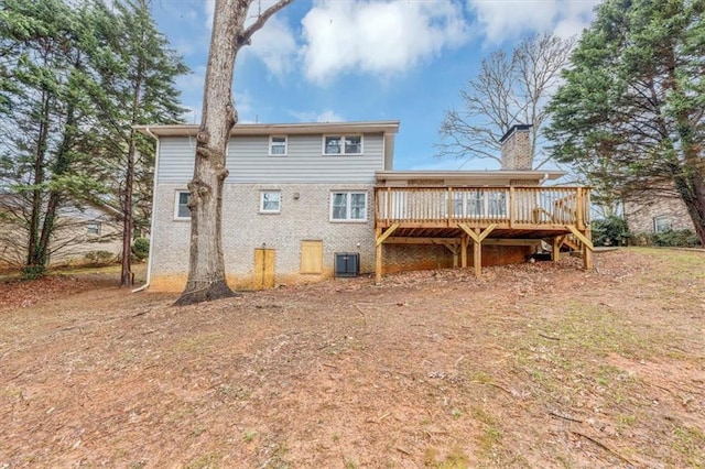 rear view of house with a deck, brick siding, a chimney, and central air condition unit