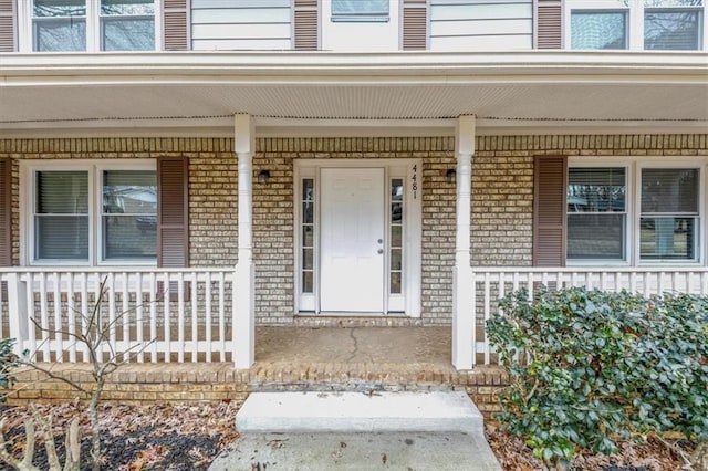 property entrance featuring a porch and brick siding