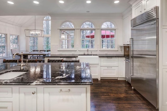 kitchen featuring hanging light fixtures, appliances with stainless steel finishes, sink, and dark stone counters