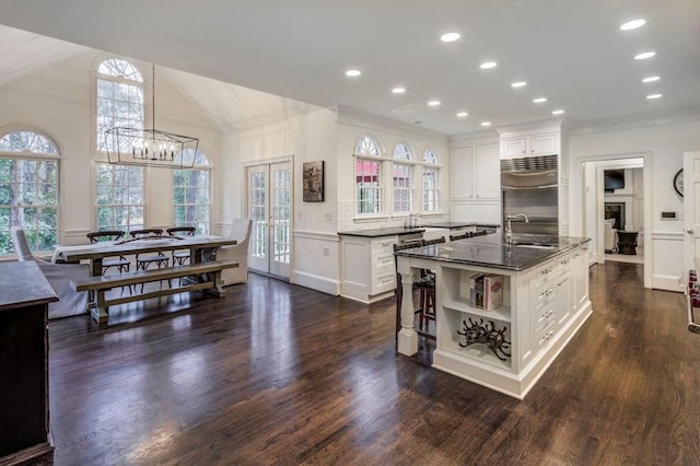 kitchen featuring a kitchen island with sink, dark wood-type flooring, white cabinets, and built in refrigerator