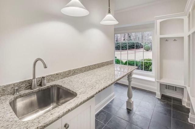 kitchen featuring sink, crown molding, white cabinetry, hanging light fixtures, and light stone counters