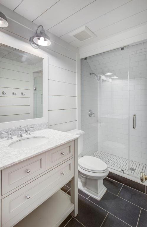 bathroom with wooden walls, vanity, an enclosed shower, tile patterned floors, and toilet