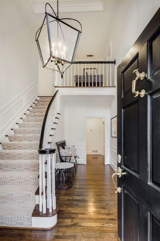 foyer entrance with crown molding, dark hardwood / wood-style flooring, and a notable chandelier