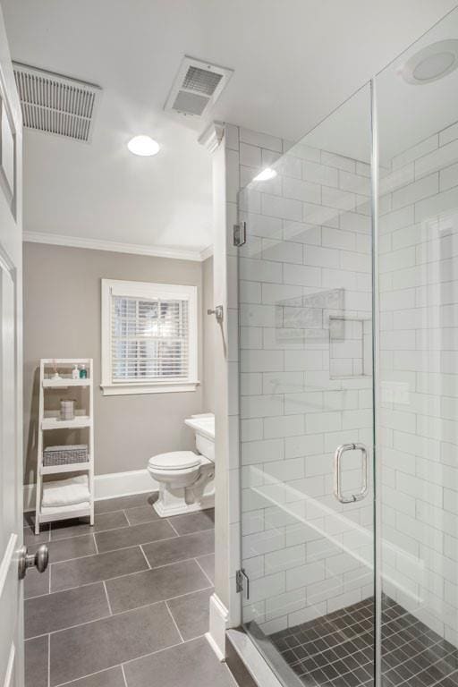 bathroom with ornamental molding, an enclosed shower, and toilet