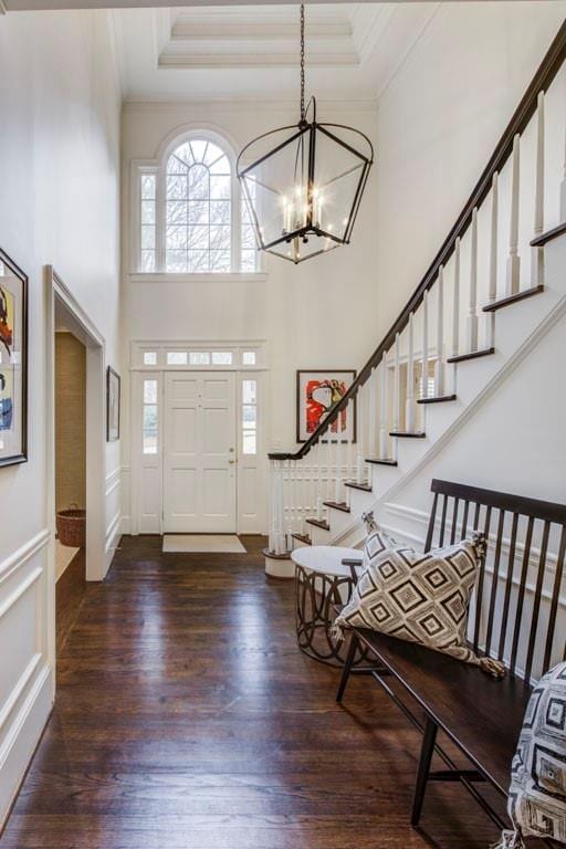 entryway featuring a chandelier, ornamental molding, dark hardwood / wood-style flooring, a tray ceiling, and a high ceiling