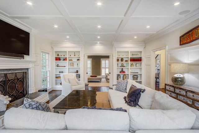 living room featuring ornamental molding, coffered ceiling, hardwood / wood-style floors, and built in features