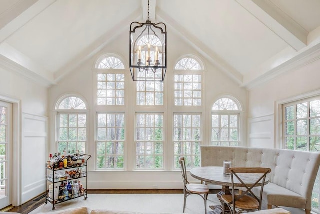 sunroom with lofted ceiling with beams and a chandelier