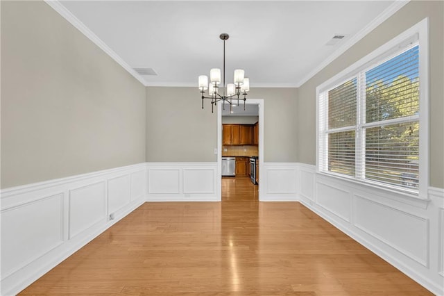 unfurnished dining area featuring crown molding, a chandelier, visible vents, and light wood-style floors