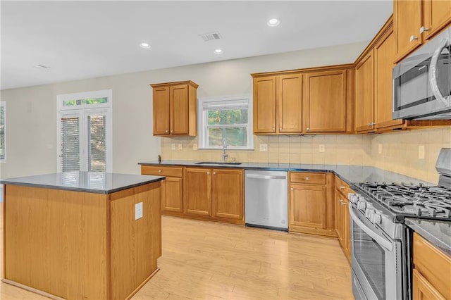 kitchen with visible vents, light wood-style floors, tasteful backsplash, a sink, and stainless steel appliances