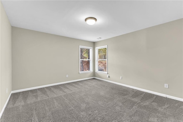 carpeted empty room featuring baseboards