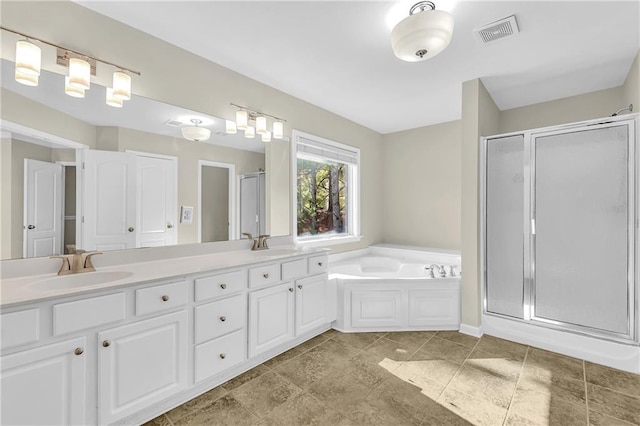 bathroom with a sink, double vanity, a shower stall, visible vents, and a garden tub