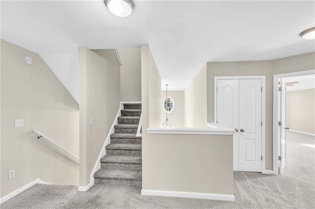 stairway featuring baseboards and carpet flooring