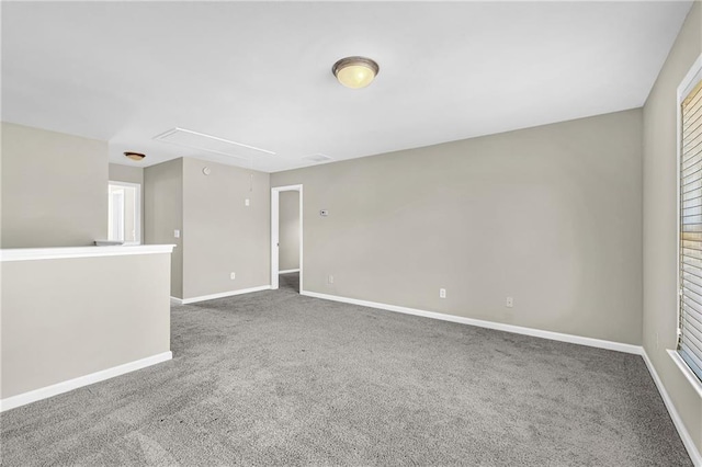 empty room featuring carpet floors, baseboards, and attic access