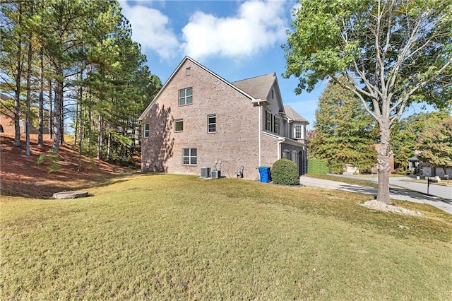view of property exterior with concrete driveway, a yard, central AC, and brick siding