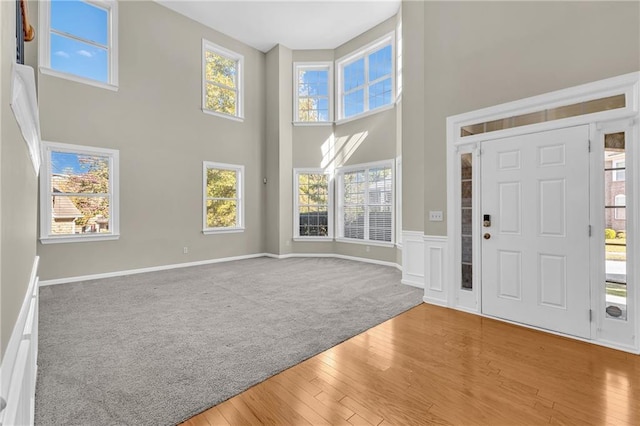 carpeted entrance foyer featuring wood-type flooring and a high ceiling