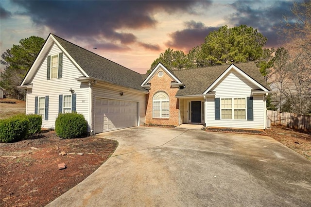 view of front of property with brick siding, fence, roof with shingles, driveway, and an attached garage