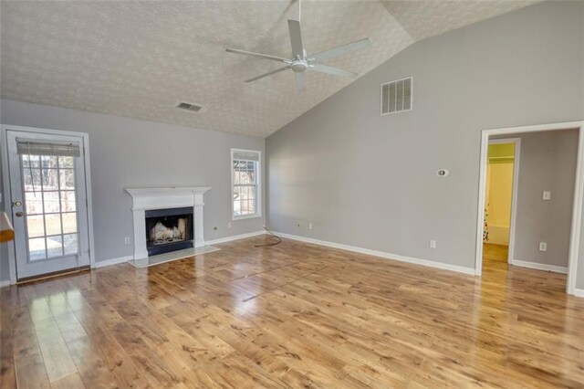 unfurnished living room with visible vents, a healthy amount of sunlight, and a fireplace with flush hearth