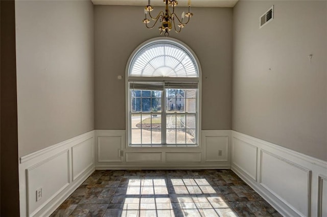 unfurnished room featuring a wainscoted wall, visible vents, a decorative wall, and an inviting chandelier