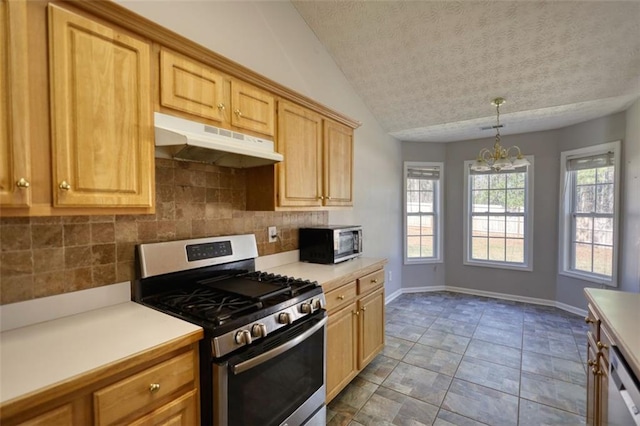 kitchen featuring stainless steel appliances, light countertops, under cabinet range hood, a notable chandelier, and backsplash