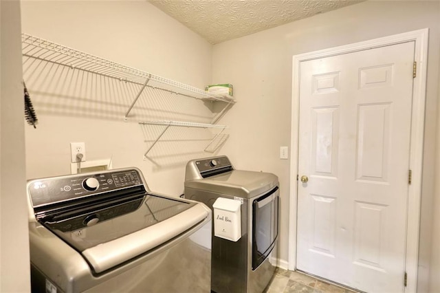 laundry area featuring laundry area, washing machine and dryer, and a textured ceiling