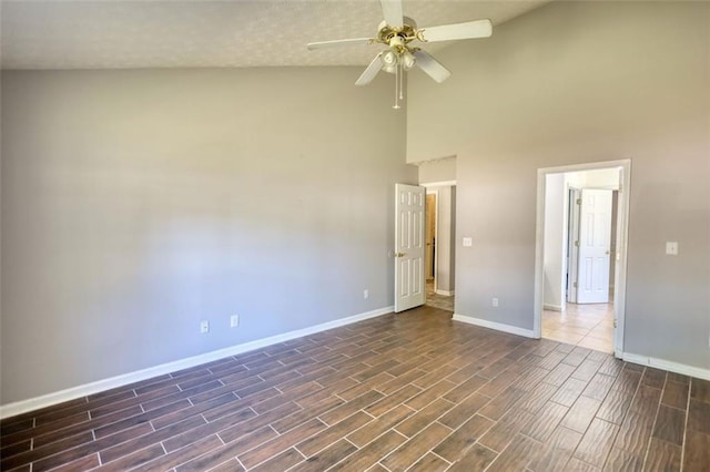 empty room with baseboards, high vaulted ceiling, dark wood finished floors, and a ceiling fan