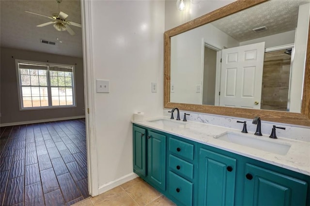 bathroom with a textured ceiling, visible vents, and a sink