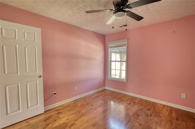 spare room with visible vents, baseboards, a textured ceiling, and wood finished floors